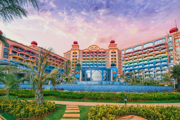A hotel with multiple colorful buildings, a central blue structure, and a well-maintained garden with a pathway. - Dolphin Bay Hotel (Yuxi)