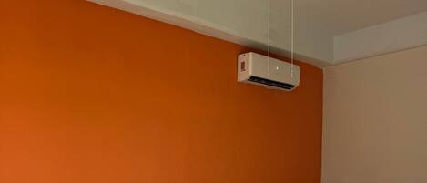 A hotel room with two beds, an air conditioning unit, a ceiling fan, and a small table with a phone.