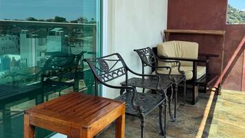 Un balcon avec une table et des chaises en bois, une paroi en verre et une vue sur la ville.
