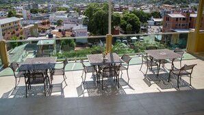 A balcony with a table and chairs overlooking a cityscape. - Fabuloso Hotel Las Vegas (Zihuatanejo)