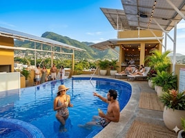 A pool area with a bar and seating, surrounded by potted plants.