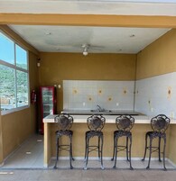 Una cocina con encimera blanca, un lavamanos y cuatro sillas ornamentadas con motivos de sol.