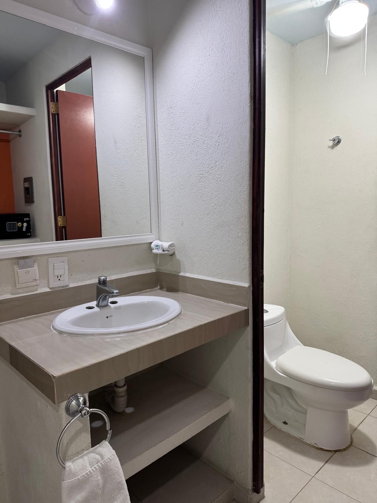 Un baño con lavamanos blanco, espejo, inodoro y ducha.