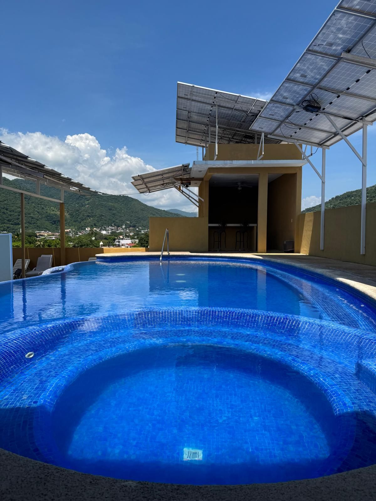 A swimming pool with a clear view of the surrounding landscape, including mountains and a clear sky.