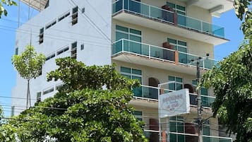 Un hôtel à plusieurs étages doté de balcons, une enseigne indiquant qu’il se trouve à Las Vegas, et une voiture blanche garée devant.