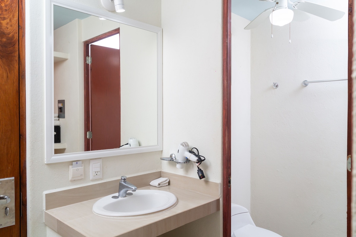 A bathroom with a white sink, a mirror, and a ceiling fan.