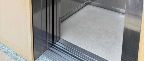 Un ascensor con puertas metálicas, una cámara de seguridad e indicador de piso.