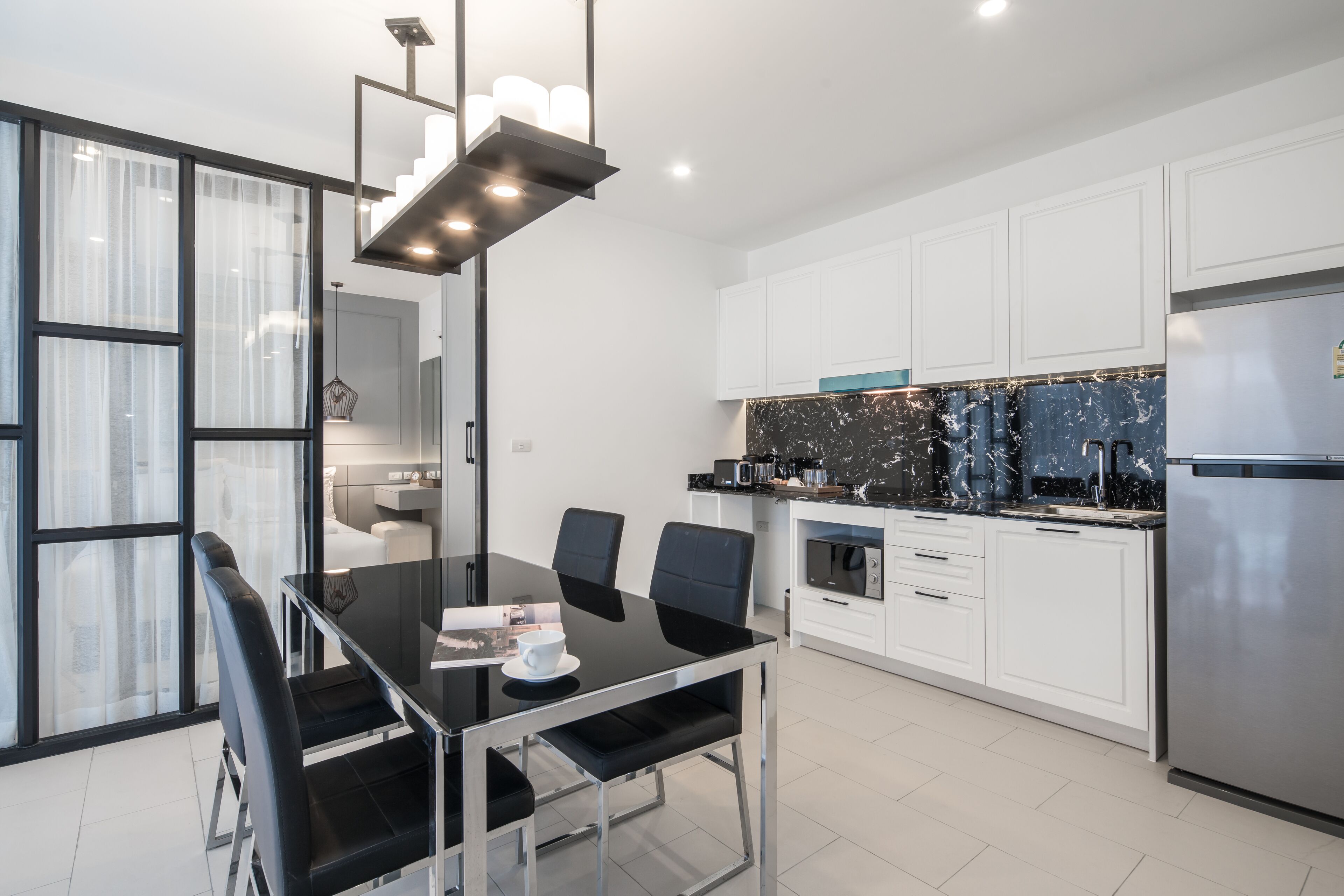A modern kitchen with white cabinets, a black marble backsplash, and stainless steel appliances.