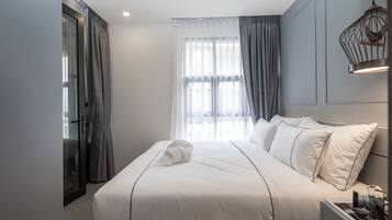 Een moderne hotelkamer met een groot bed, een nachtkastje, een raam met gordijnen en een hangende lamp.
