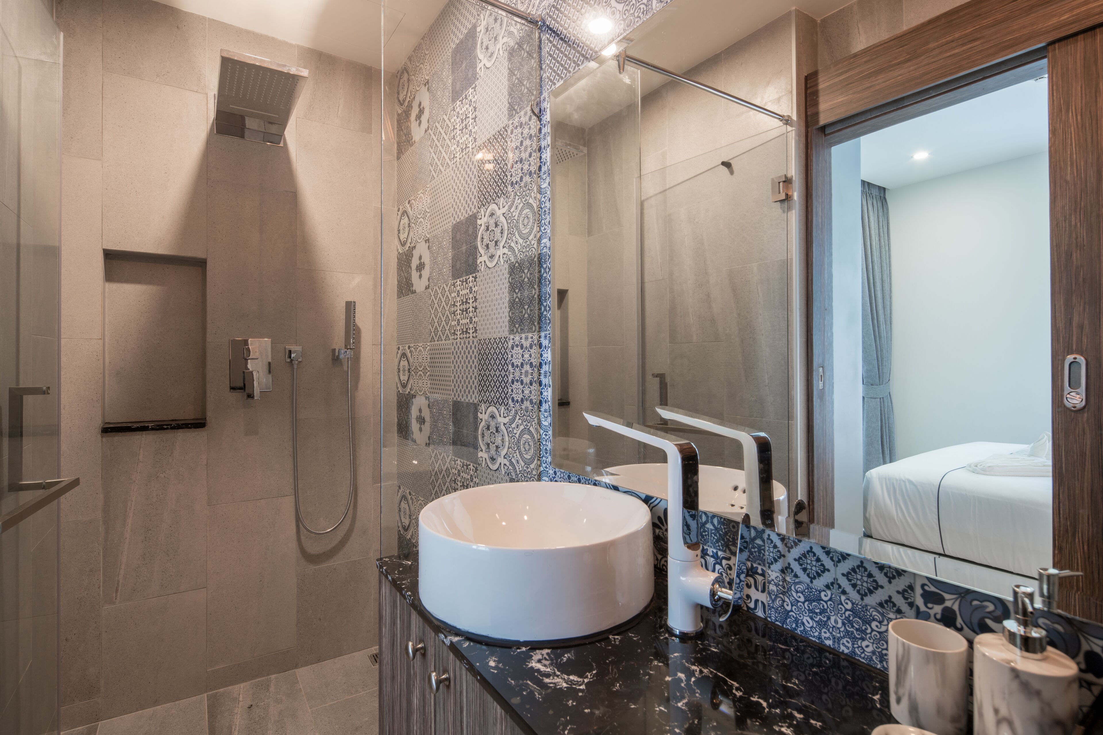 A modern bathroom with a large mirror, a round sink, and a shower area.