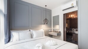 Habitació d'hotel moderna amb un llit gran, una taula de nit, un mirall i un armari encastrat.