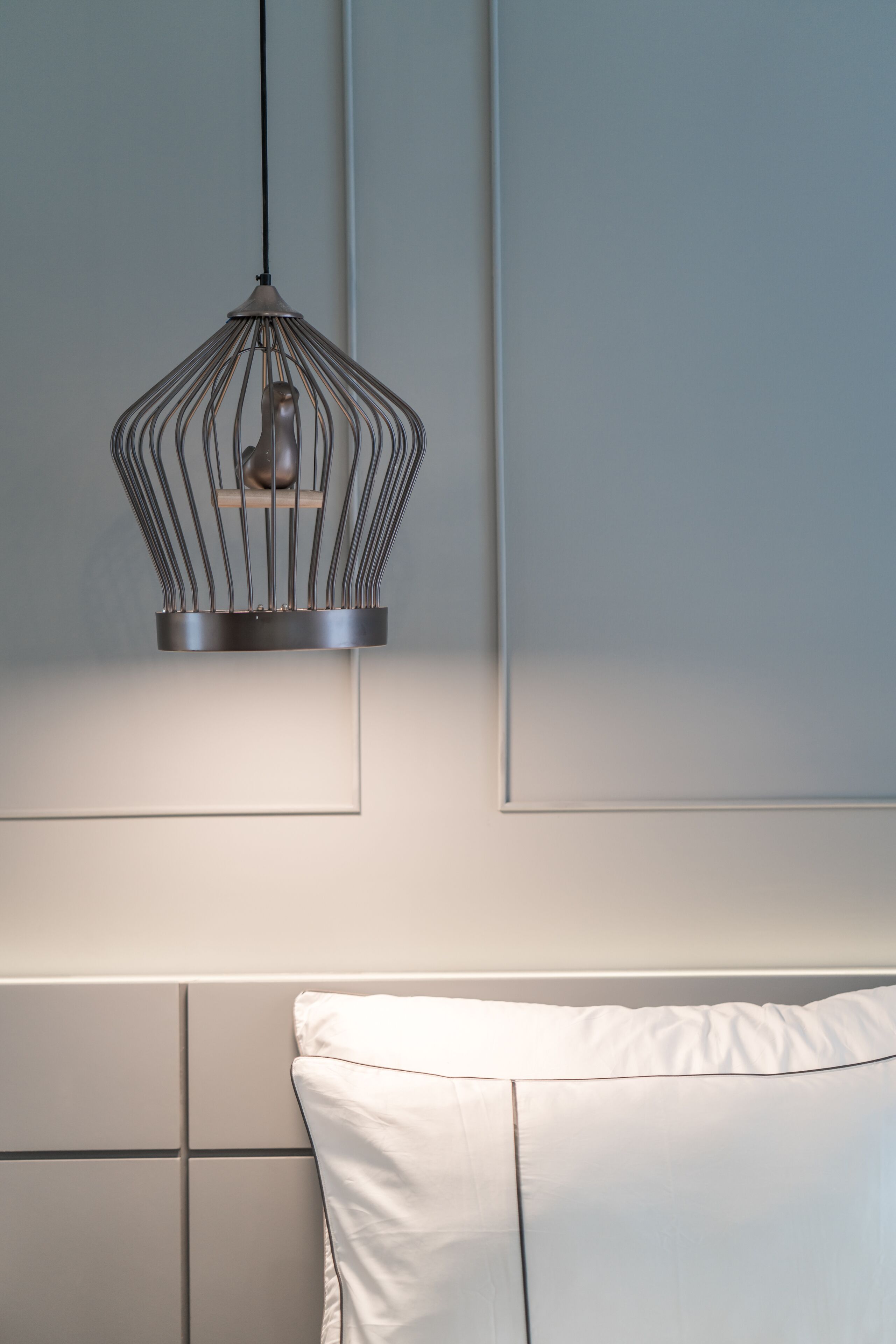 A modern bedroom with a hanging light fixture, a white pillow, and a tiled headboard.