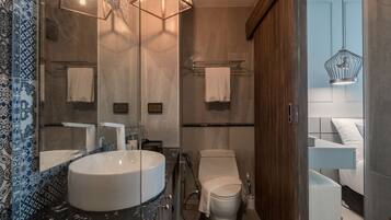 A modern bathroom with a large sink, toilet, and shower area.