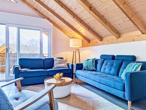 Un salon moderne avec un canapé bleu, une table basse ronde et une lampe.