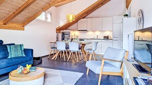 Ein moderner Wohnbereich im Loft-Stil mit Esstisch, Stühlen und einer Küche im Hintergrund.