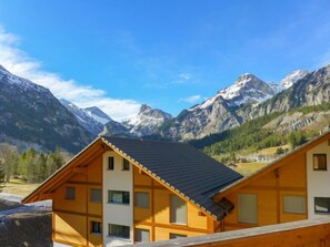 Un edificio in stile chalet con tetto spiovente, numerose finestre e vista sulle montagne innevate.