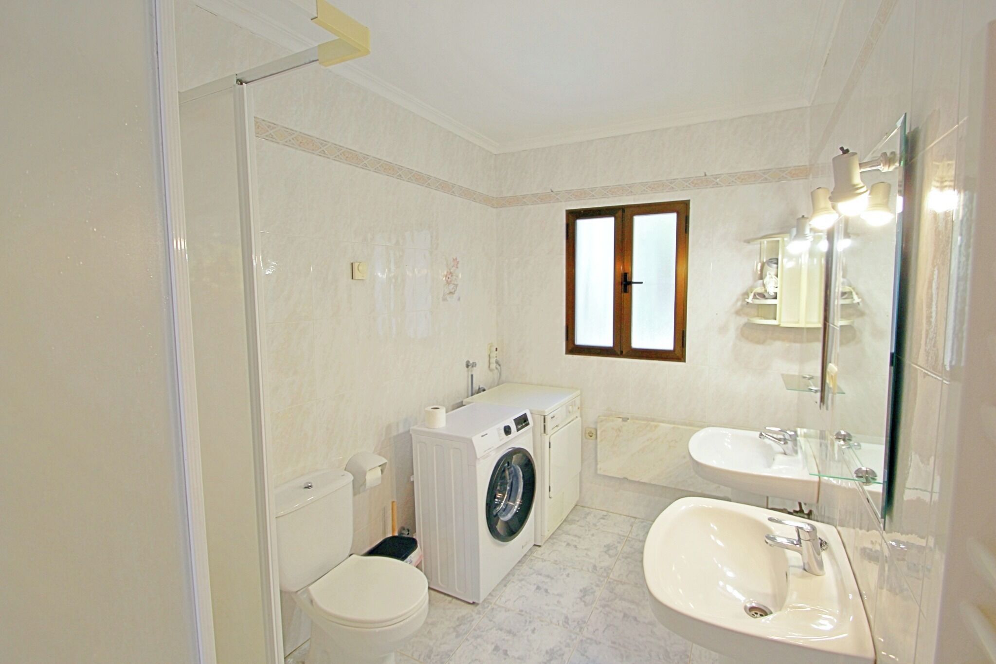 Une salle de bain équipée d’un lave-linge, de toilettes, d’un lavabo et d’une fenêtre.