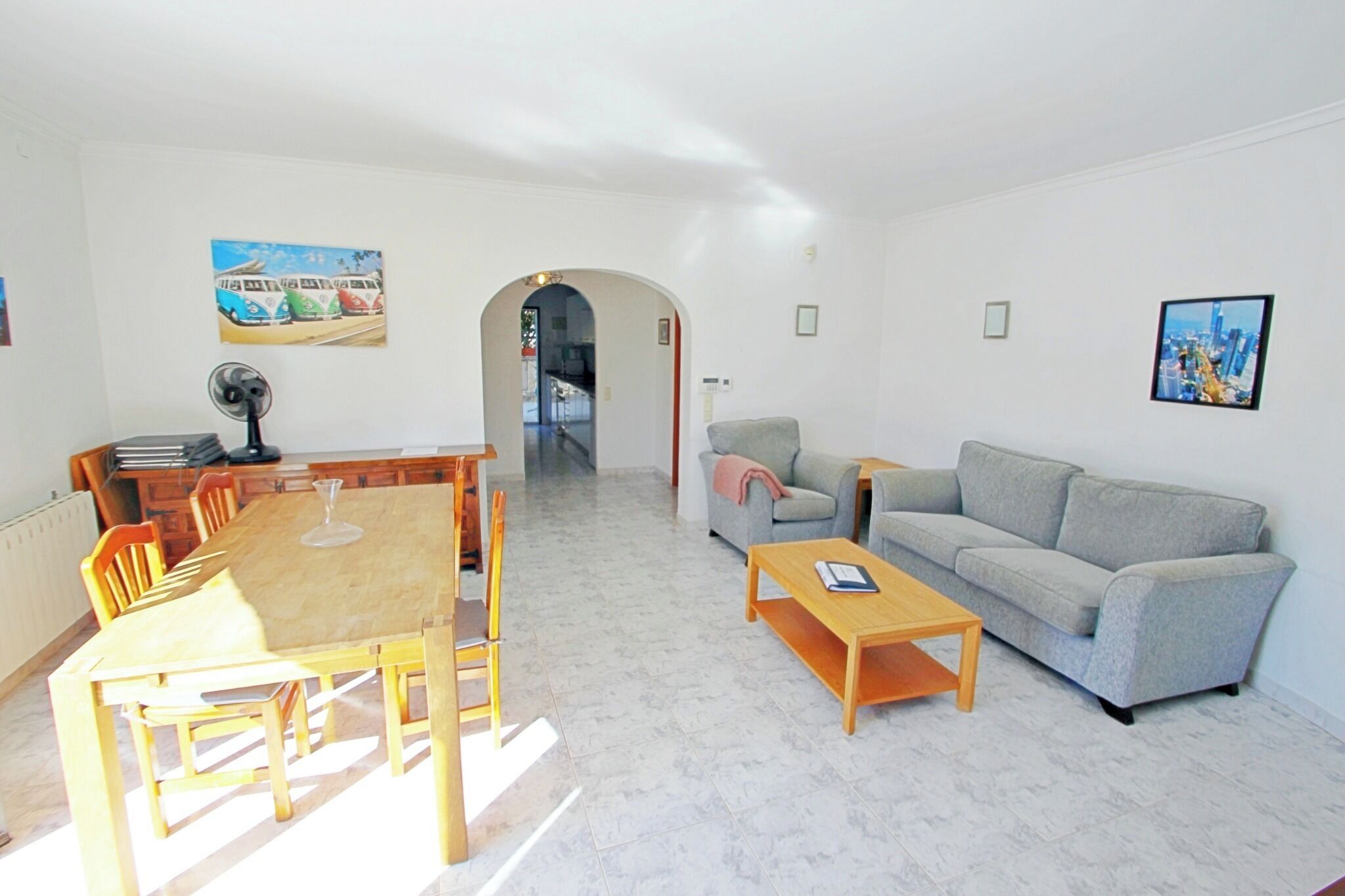 A spacious living area with a dining table, chairs, a sofa, and a coffee table.