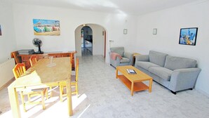 En rummelig opholdsstue med spisebord, stole, sofa og sofabord.