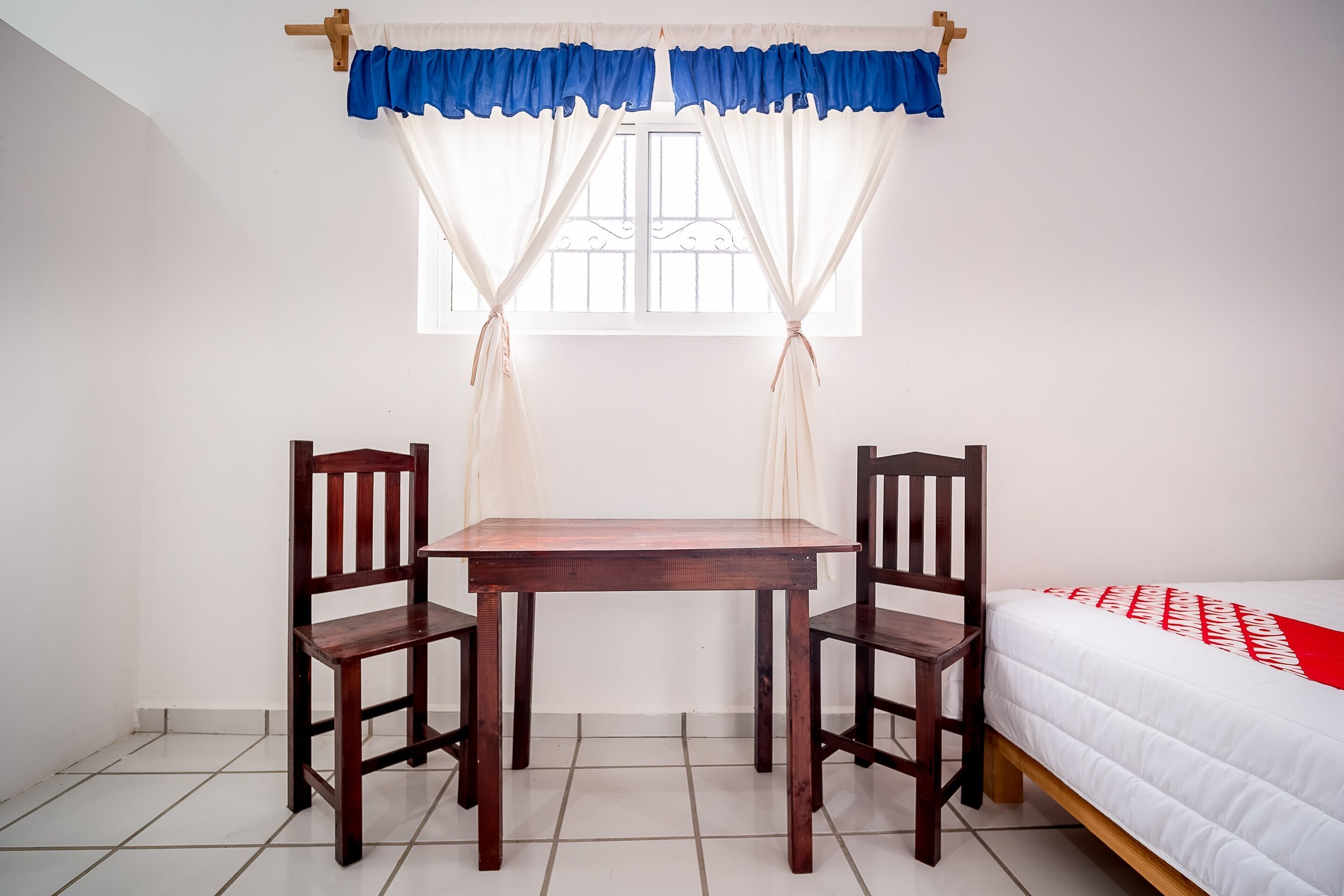 A room with a bed, a table, and two chairs.
