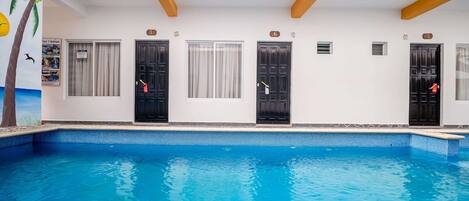 A hotel with a swimming pool, numbered rooms, and a mural of a palm tree.