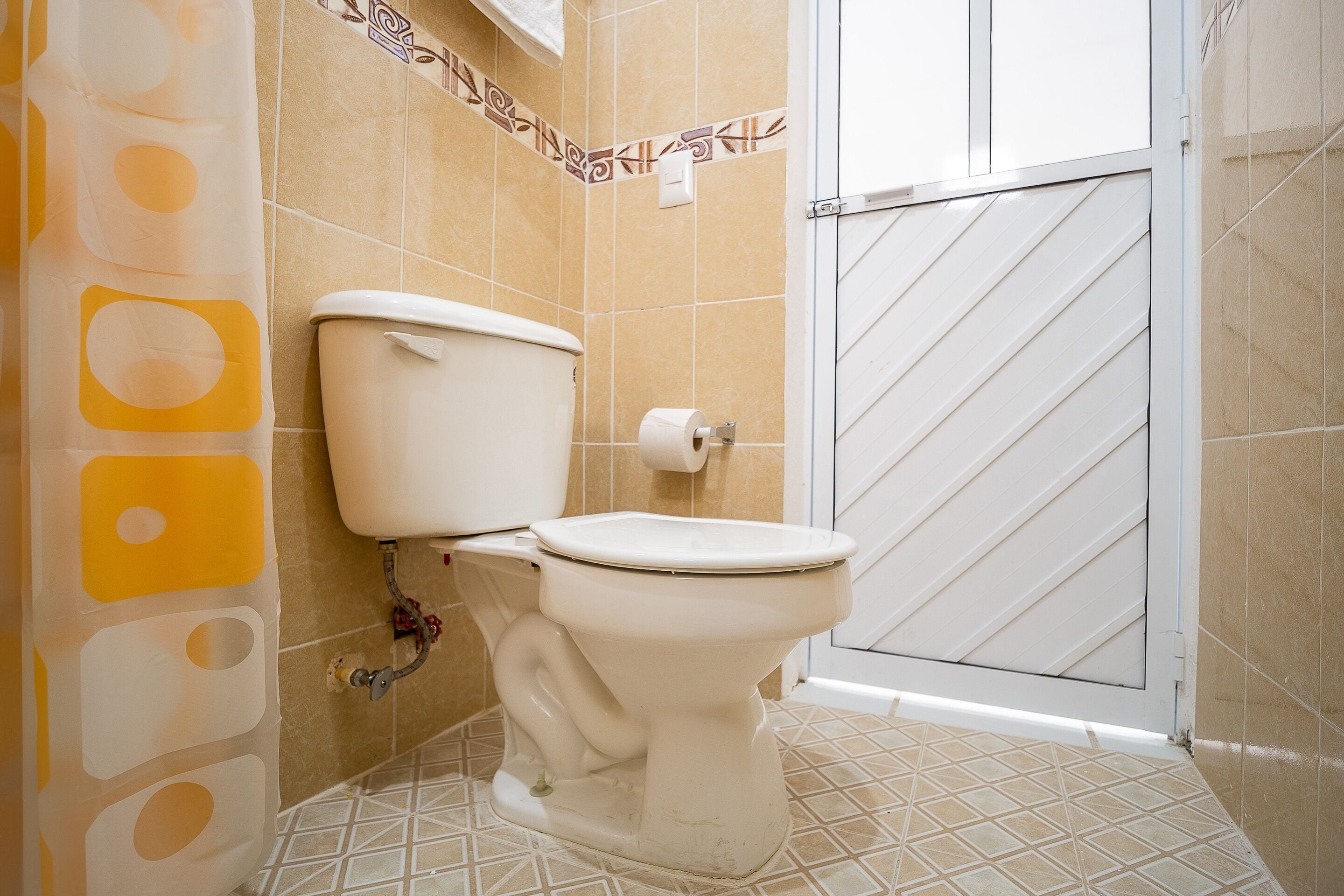 Un baño con inodoro, ducha y piso de baldosas.