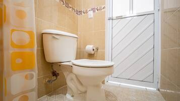 Un baño con inodoro, ducha y piso de baldosas.