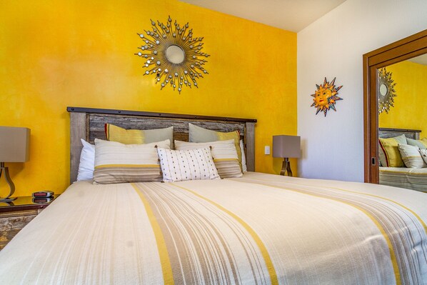 Una habitación de hotel con una cama grande, un cabecero de madera, dos lámparas de noche y un espejo en la pared.