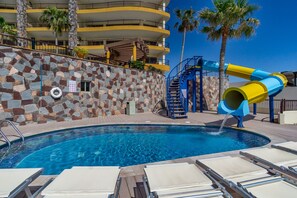 Relax by the pool surrounded by lounge chairs and a vibrant water slide.