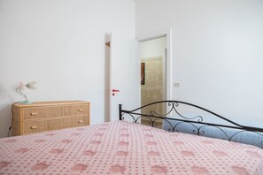 Une chambre à coucher comprenant un lit, une commode et une porte donnant sur une autre pièce.