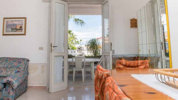 Une pièce comprenant une table à manger, des chaises, un canapé et un grand miroir.