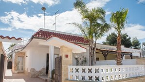Une maison avec un toit en tuiles, un mur en pierre et une clôture blanche ornée de motifs en forme de papillons.