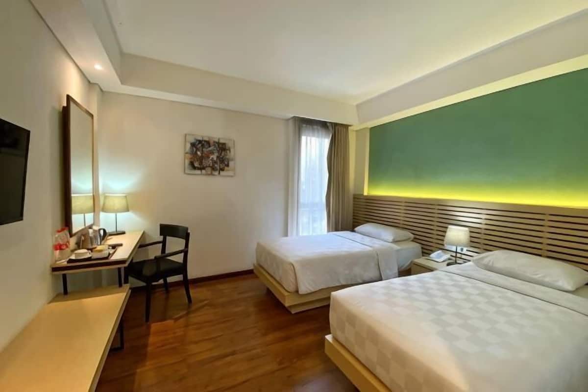 Una habitación de hotel con dos camas, un escritorio, una silla, un televisor y un cuadro en la pared.