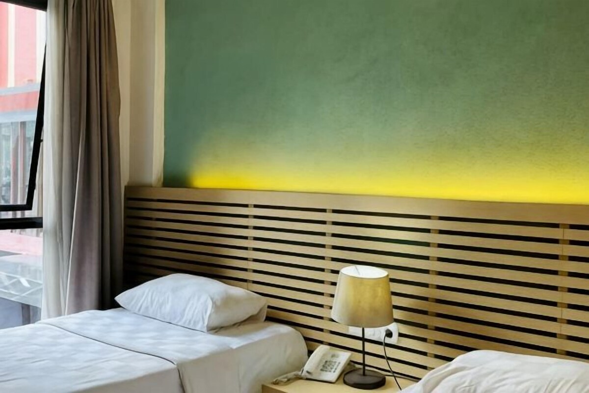 A hotel room with a bed, a bedside table with a lamp, and a telephone.