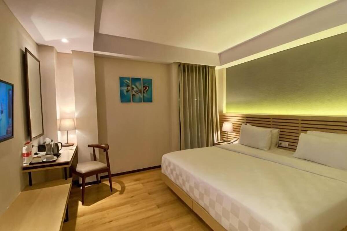 Una habitación de hotel con cama, escritorio, silla y televisor.