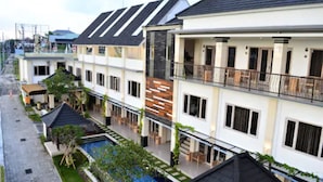 Un hotel moderno de varios pisos con balcones, piscina y un jardín bien cuidado.