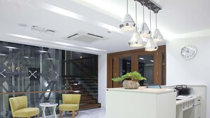 Un espacio de oficina moderno con un mostrador de recepción, dos sillas amarillas, una planta en maceta y una escalera.