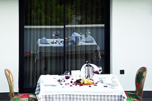 A dining table set for two with a checkered tablecloth, two wine glasses, a pitcher, and a fruit platter. - Casa Bianca Hotel (Denizli)