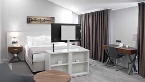 Una habitación de hotel moderna con una cama, un escritorio, una silla, una mesita y un televisor.