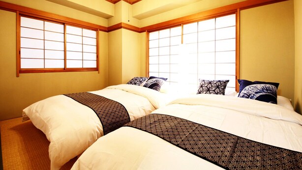 A traditional Japanese-style bedroom with two beds, large windows, and a wooden ceiling. - GrandTree ATAMI KAIKO-INN (Atami)