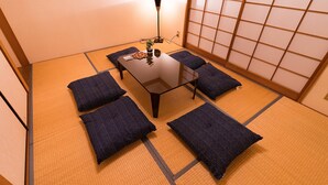 A tatami mat room with a low table, four cushions, a floor lamp, and a shoji screen. - GrandTree ATAMI KAIKO-INN (Atami)