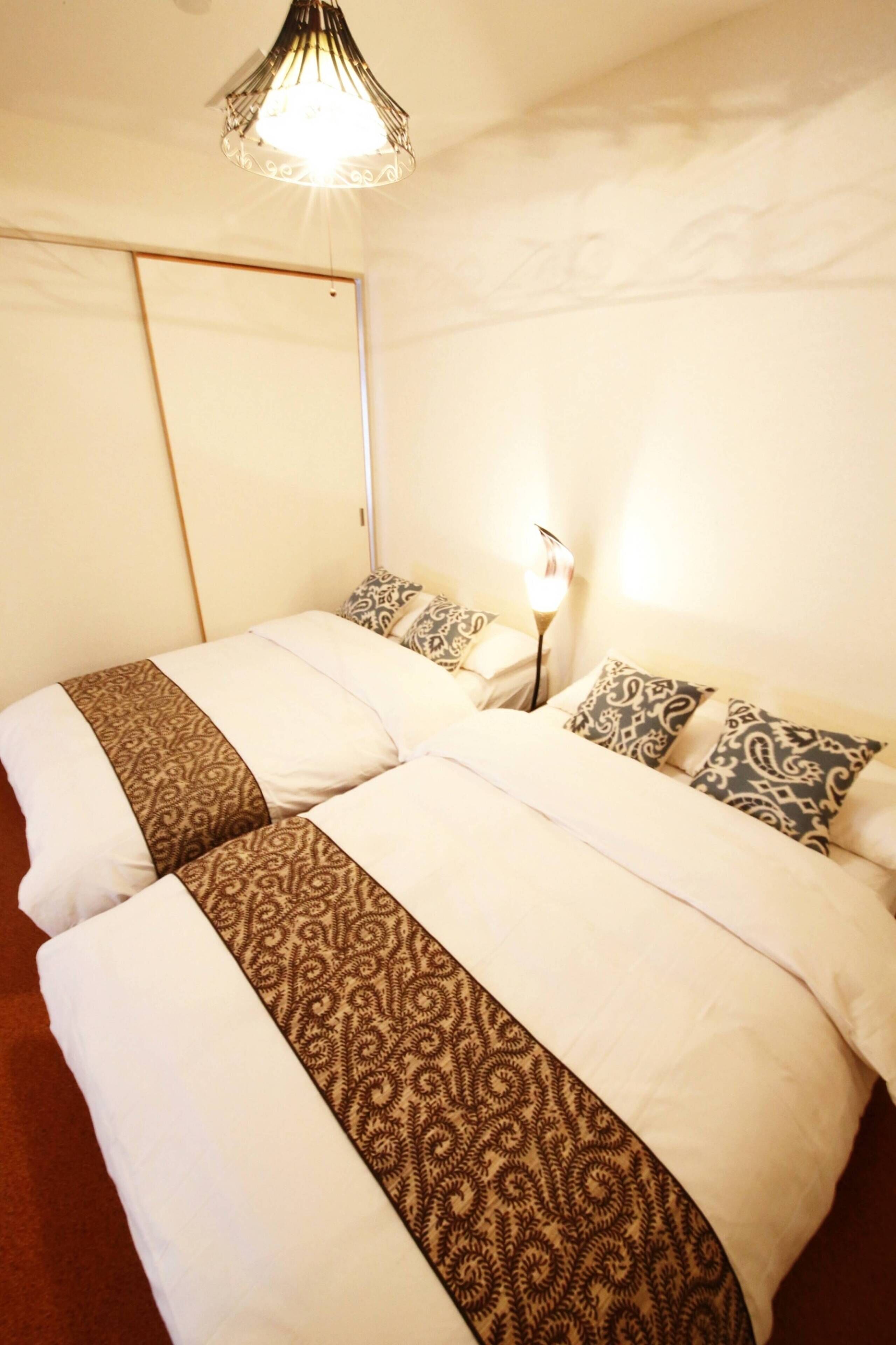 Una cama doble con ropa de cama estampada, una mesita de noche con lámpara y un armario en una habitación de hotel.