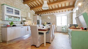 Una cucina rustica con pareti in pietra, travi in legno e un'area pranzo con un tavolo apparecchiato per quattro persone.