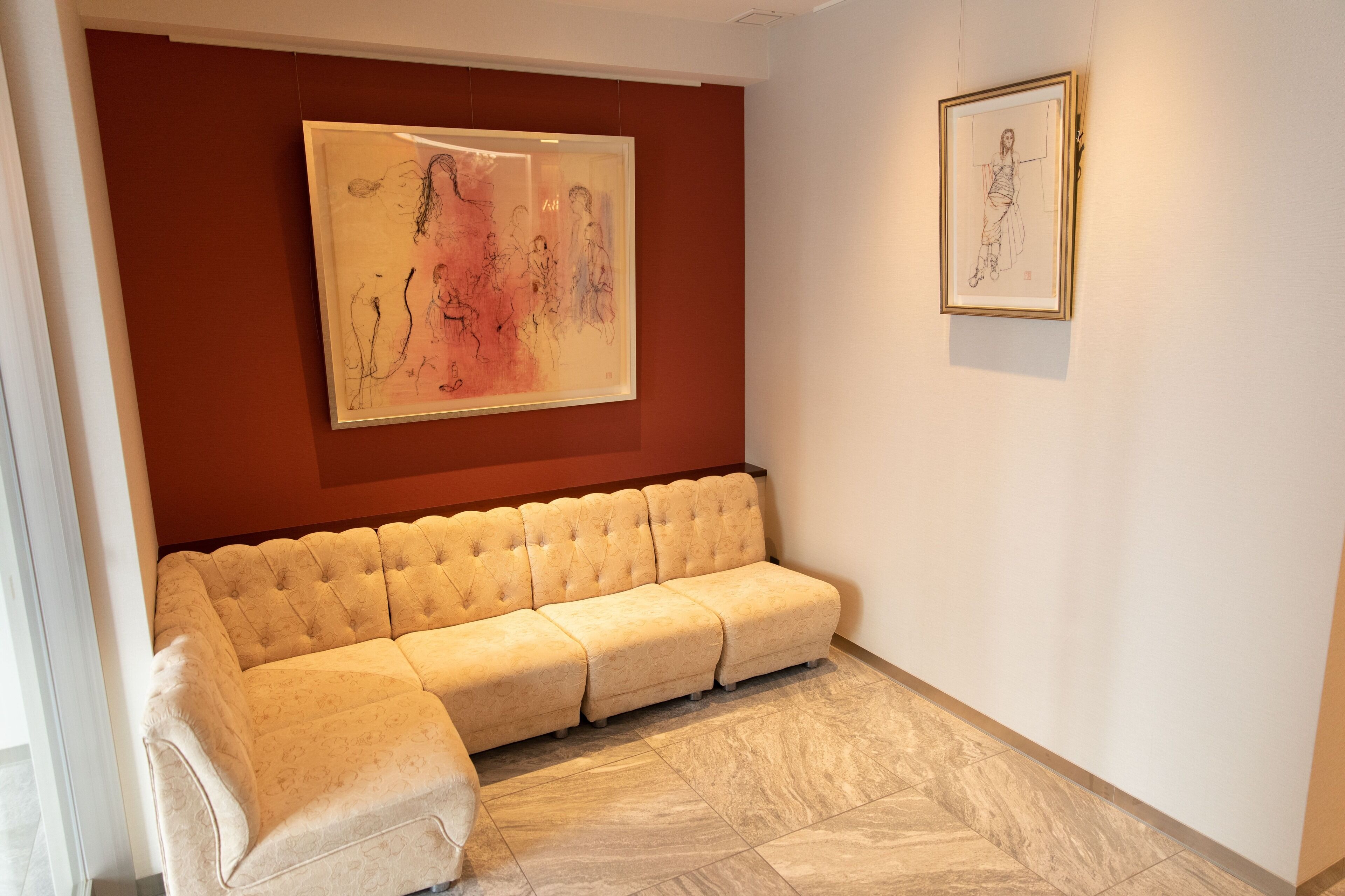 Un salon moderne avec un canapé d’angle beige, une grande peinture abstraite et une esquisse encadrée accrochée au mur.