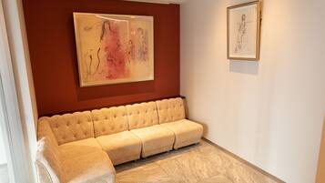 Un salon moderne avec un canapé d’angle beige, une grande peinture abstraite et une esquisse encadrée accrochée au mur.
