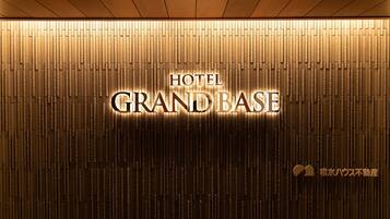 A wall with vertical wooden slats and illuminated text reading "HOTEL GRAND BASE".