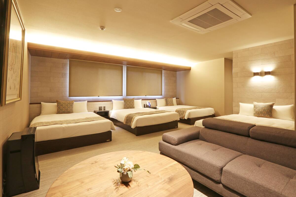 Ein Hotelzimmer mit zwei Betten, einem Schlafsofa, einem Couchtisch und einem Fernseher.