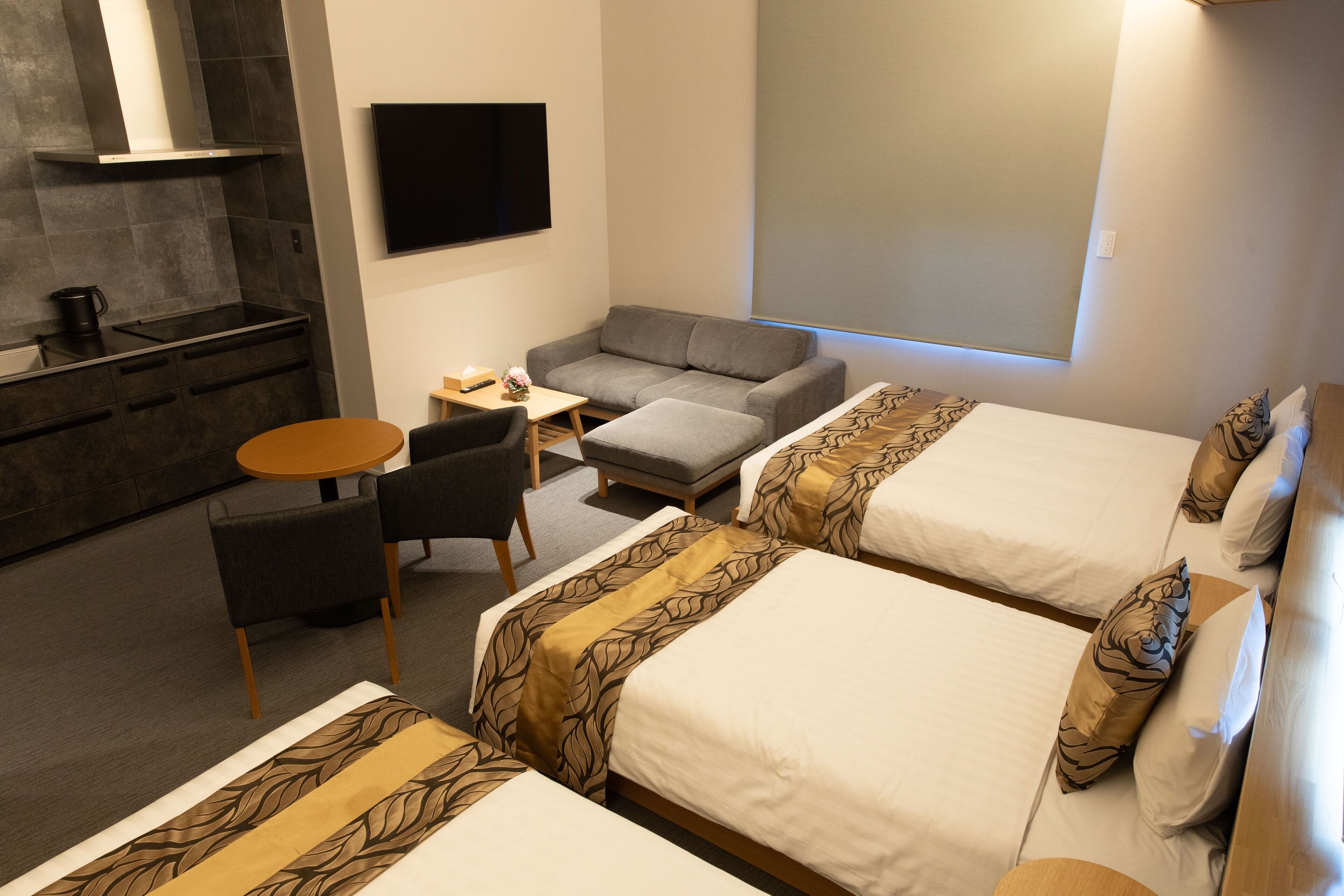A hotel room with two beds, a sofa, a small table, and a TV.