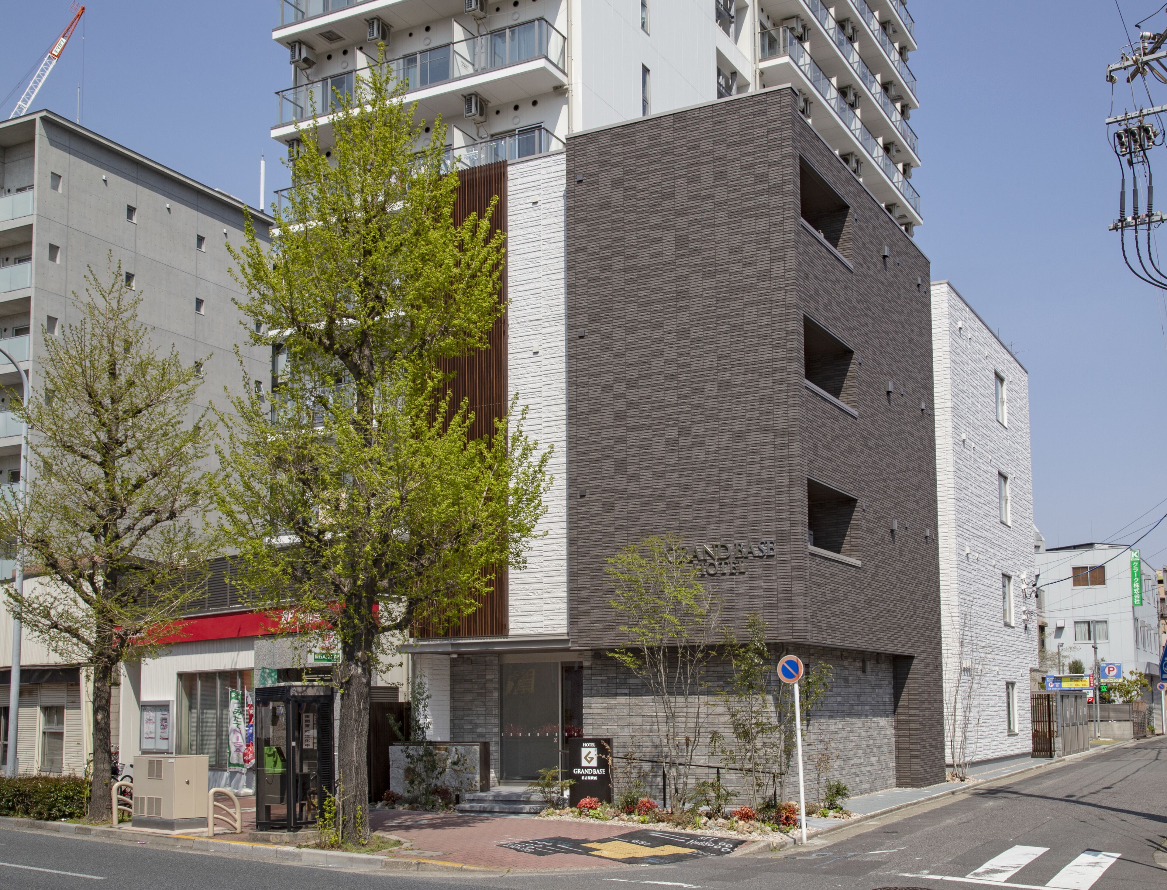 A modern hotel with a brick facade and a large tree in front.