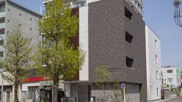 A modern hotel with a brick facade and a large tree in front.